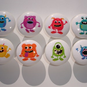 May include: Eight colorful monster-themed cabinet knobs. Each knob is round and white with a different monster design. The monsters are blue, pink, red, orange, green, and blue.