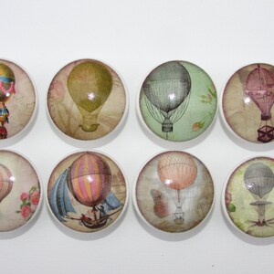 May include: Eight round ceramic knobs with vintage hot air balloon designs. Each knob features a different colored balloon with a unique design and background.