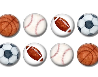 May include: Six round buttons with images of different sports balls. The buttons feature a basketball, baseball, football, and soccer ball. The buttons are white with a glossy finish.