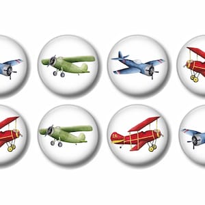 May include: Set of eight round buttons featuring watercolor illustrations of vintage airplanes in blue, green, and red. The designs include biplanes and single-wing aircraft, with propeller details.