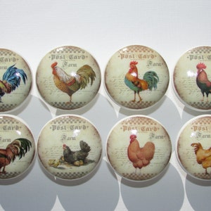 May include: Eight ceramic knobs with a vintage postcard design featuring roosters and hens. The knobs have a white background with a brown and white checkered border. The text on the knobs reads "Post Card Farm".