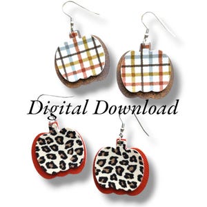 May include: Two pairs of pumpkin-shaped earrings. One pair features a plaid pattern in shades of brown, white, and blue. The other pair features a leopard print pattern in shades of brown, white, and black.