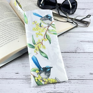 May include: White eyeglass case with a floral pattern featuring blue birds and yellow flowers. The case is made of fabric and has a zipper closure.