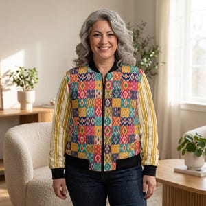 May include: A bomber jacket featuring a vibrant, multi-colored patchwork pattern of geometric shapes on the front and back panels, contrasted by yellow and white vertical striped sleeves, a black ribbed collar, cuffs, and hem, and a central black zipper.