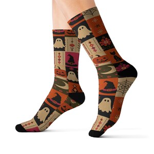 Peut inclure: Une paire de chaussettes montantes avec un motif patchwork sur le thème d'Halloween, incluant des fantômes blancs, des citrouilles orange, des chapeaux de sorcière noirs, des chats noirs, des toiles d'araignée, des lunes et des fleurs.