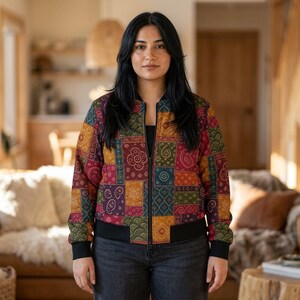 Può includere: Un giubbotto bomber a maniche lunghe con un motivo patchwork multicolore caratterizzato da vari disegni geometrici e floreali nelle tonalità del rosso, giallo, verde e blu scuro. La giacca presenta colletto, polsini e orlo a coste neri.