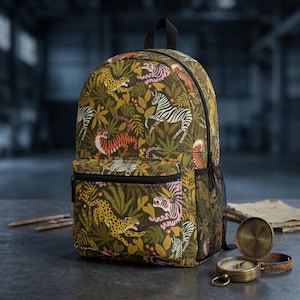 Pode incluir: Uma mochila com um padrão de selva verde-escuro com ilustrações de tigres, leopardos e zebras em tons de laranja, amarelo, rosa e branco. A bolsa inclui um bolso frontal com fecho, fechos pretos e um bolso lateral de rede preta.