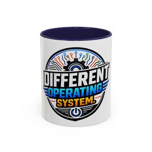 May include: A white ceramic mug with a dark blue interior and rim. The front features a circular graphic with a black gear, circuit board lines in orange, blue, and green, and the text "DIFFERENT OPERATING SYSTEM." with a power button icon.