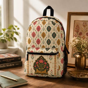 May include: A backpack featuring an off-white base with a repeating pattern of pink, gold, and teal floral motifs. The front pocket displays a large, ornate archway design containing a central flower and two small golden leopards at the base.