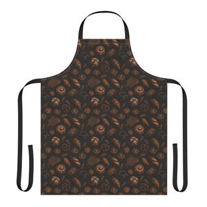 May include: A black apron featuring a repeating pattern of brown-toned baked goods, including croissants, pretzels, round loaves, and biscuits. The apron has a neck loop and two side ties, all in solid black, providing a consistent dark background.