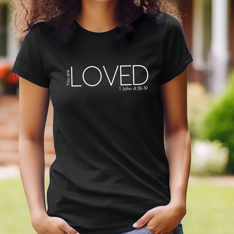 Może przedstawiać: Czarny T-shirt z białym napisem "You are LOVED 1 John 4:18-19".