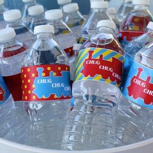 Op de afbeelding: Een close-up van een koeler gevuld met waterflessen versierd met blauwe, rode en gele treinetiketten waarop "Chug Chug Chug" staat.