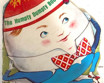 Puede incluir: Un libro infantil con forma troquelada titulado The Humpty Dumpty Book, que muestra un personaje con forma de huevo que lleva un sombrero rojo con flores de lis amarillas, una pajarita de cuadros rojos y blancos y pantalones azules, con 29 centavos.