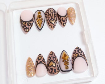 Uñas postizas con punta francesa, estampado de leopardo y detalles dorados.