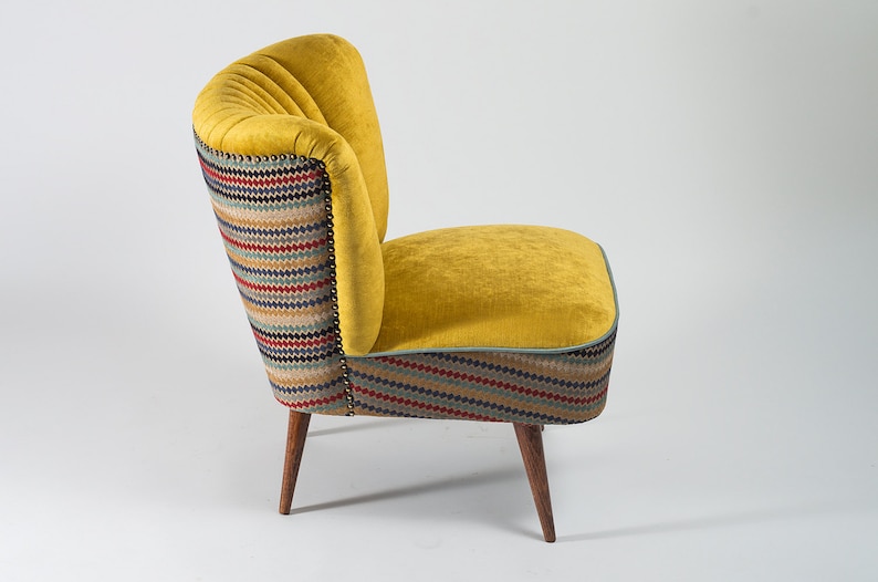 May include: A yellow armchair with a striped fabric back and seat. The chair has wooden legs and a tufted back.