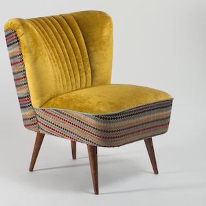 May include: A yellow velvet armchair with a patterned fabric base and wooden legs.