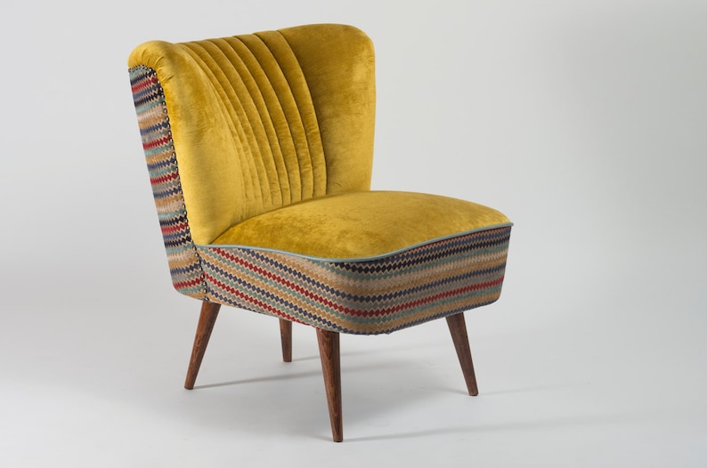 May include: A yellow velvet armchair with a patterned fabric base and wooden legs.