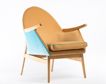 May include: A tan leather armchair with a blue velvet insert and wooden legs. The chair has a curved back and armrests.