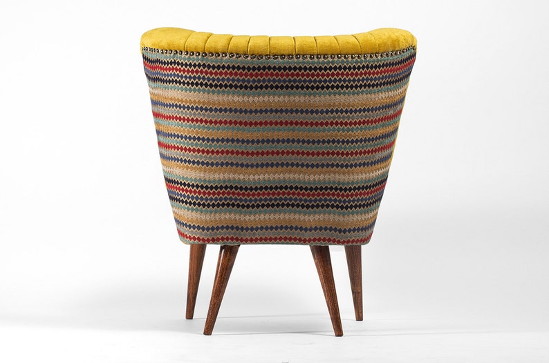 May include: A yellow armchair with a colorful striped fabric upholstery and wooden legs. The chair has a rounded back and a tufted design.