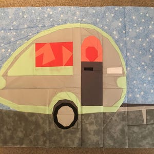 Op de afbeelding: Een lichtgroene en grijze camper met een rood raam en een grijze deur. De camper staat op een blauwe achtergrond met witte sterren.