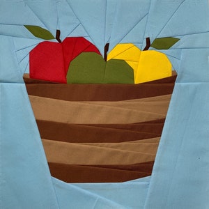 May include: A brown basket with a red, green, and yellow apple inside. The basket is made of fabric and has a striped pattern.