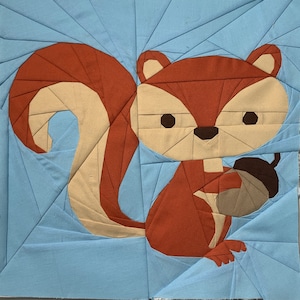 May include: A brown and tan paper craft squirrel holding an acorn. The squirrel is on a light blue background.
