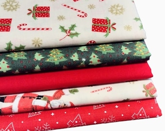 May include: A stack of five fabric squares with Christmas-themed prints. The top square is cream with red and green Christmas presents, candy canes, and snowflakes. The second square is green with small Christmas trees. The third square is red. The fourth square is cream with Santa Claus and candy canes. The bottom square is red with white snowflakes.