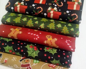 May include: A stack of Christmas-themed fabric pieces. The fabrics feature festive patterns including gift boxes, candy canes, Christmas trees, gingerbread men, holly, and snowmen. Colors include black, green, red, and tan.