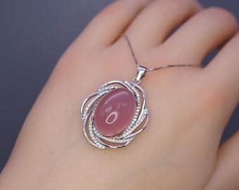 May include: A silver necklace with a pink oval gemstone pendant surrounded by a silver swirl design with clear cubic zirconia stones.