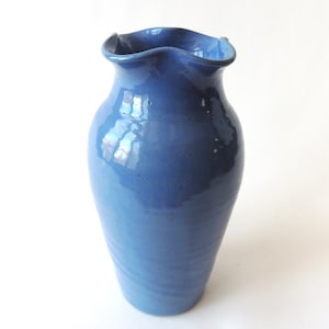 May include: A blue ceramic vase with a wavy rim. The vase has a smooth, glossy finish.