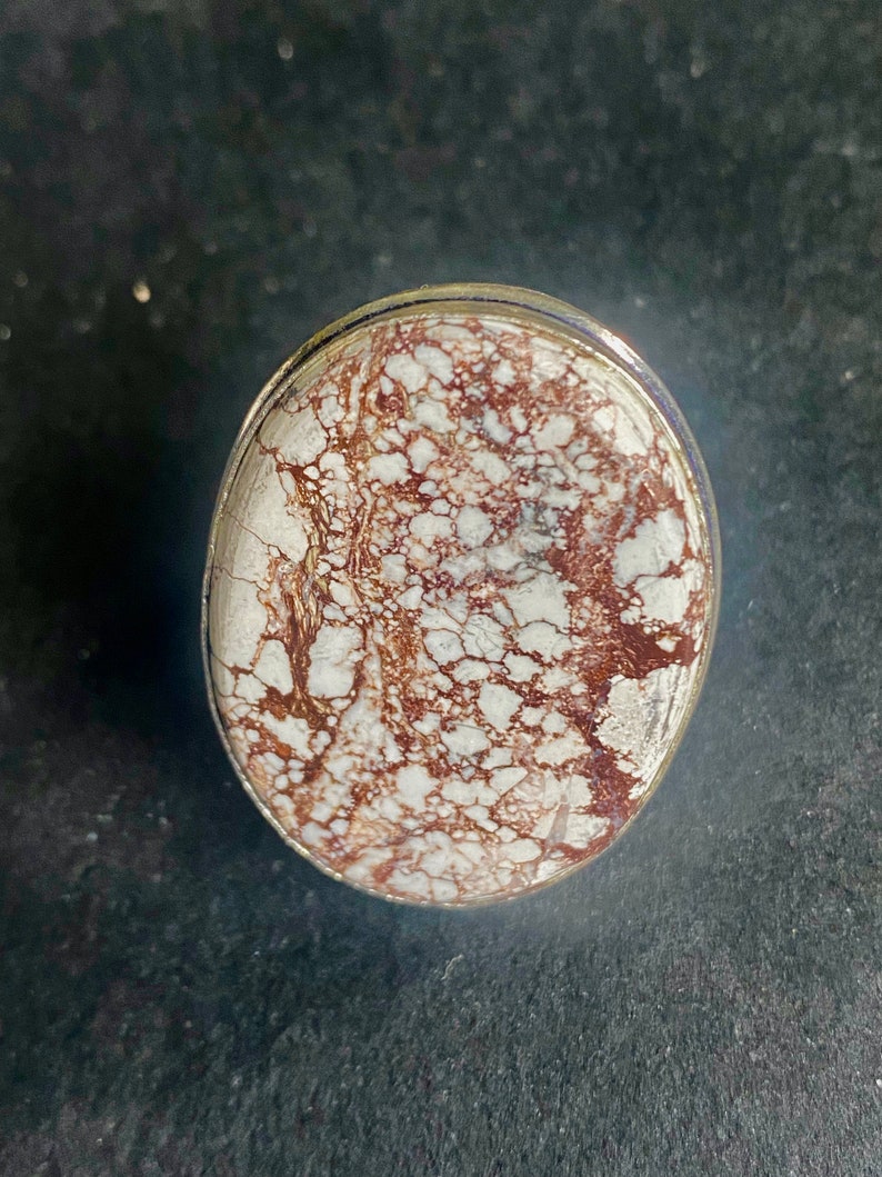 K&ouml;nnte beinhalten: Nahaufnahme eines Rings aus wei&szlig;em und braunem Achat mit einer silbernen Fassung. Der Achat hat ein wirbelndes Muster aus Wei&szlig; und Braun.