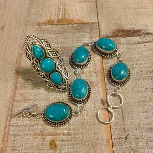 K&ouml;nnte beinhalten: Ein Ring- und Armband-Set aus T&uuml;rkis und Silber. Der Ring hat drei T&uuml;rkis-Steine und das Armband hat f&uuml;nf T&uuml;rkis-Steine.
