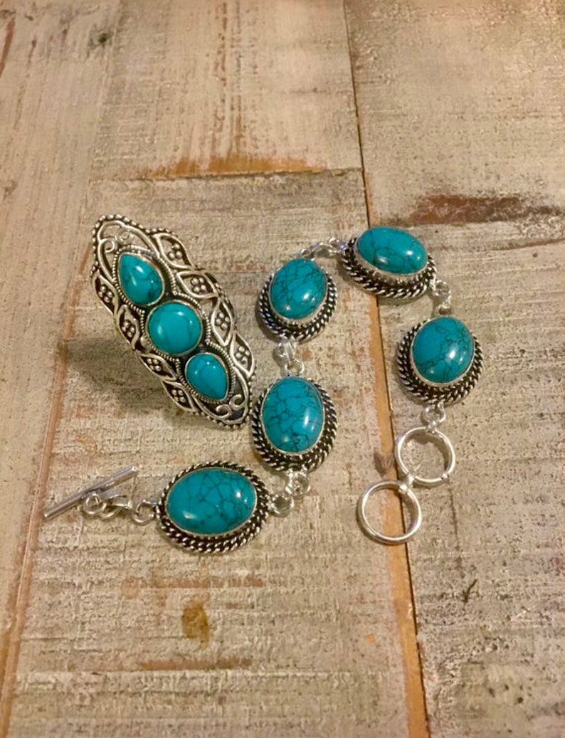 K&ouml;nnte beinhalten: Ein Ring- und Armband-Set aus T&uuml;rkis und Silber. Der Ring hat drei T&uuml;rkis-Steine und das Armband hat f&uuml;nf T&uuml;rkis-Steine.