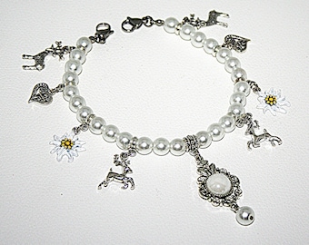 May include: A white pearl bracelet with silver charms, including a heart, a deer, a flower, and a snowflake. The bracelet has a silver clasp and a silver pendant with a white stone.