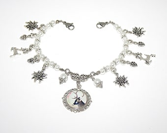 May include: A silver-toned charm bracelet featuring white faux pearls and various metal charms including edelweiss flowers, pinecones, a deer silhouette, and a central circular pendant with a deer image, secured with a lobster claw clasp.