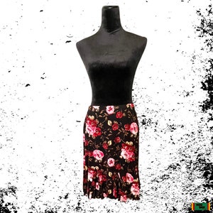 May include: A black skirt with a floral print featuring pink and red roses on a dark brown background. The skirt has a ruffled hem.