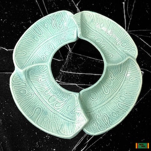 May include: A light green ceramic serving dish with four sections. The dish has a textured design that resembles leaves.
