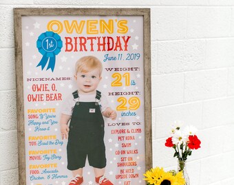 May include: A framed birthday poster with the text "Owen's Birthday" and a photo of a child. The poster includes the child's weight (21 lbs) and height (29 inches). A vase of flowers sits nearby.