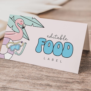 May include: A light pink, folded food label with a cartoon flamingo, snorkel, and life preserver illustration. The words "editable FOOD LABEL" are printed in blue and black. The label is on a wooden surface.