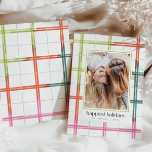 May include: Holiday greeting cards with a plaid pattern in red, green, and pink. One card features a family photo with the text "happiest holidays" and the family name. The cards are on a white background.