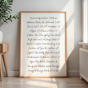 Puede incluir: Una impresión enmarcada con un marco de madera clara muestra una lista de nombres en escritura negra. El texto incluye frases como "Heavenly Father Elohim" y "King of Kings Lord of Lords". La impresión se muestra en interiores cerca de una ventana.
