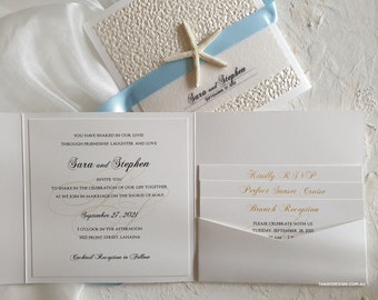 Op de afbeelding: Elegant trouwuitnodigingspakket met een witte kaart met textuur, lichtblauw lint en een zeesteraccent. De uitnodiging bevat de namen "Sara en Stephen" en evenementdetails.