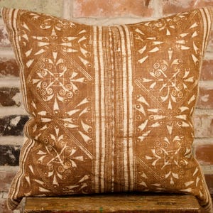 May include: A brown and white patterned throw pillow with a geometric design. The pillow is made of a soft, woven fabric.