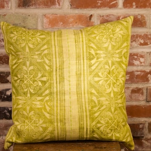 May include: A yellow and green patterned throw pillow with a decorative design. The pillow is made of a soft, woven fabric.