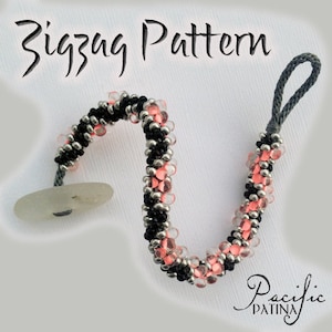 May include: A black, silver, and pink beaded bracelet with a gray cord and a button closure. The bracelet features a zigzag pattern and the text "Zigzag Pattern".