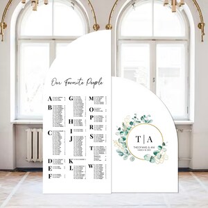 May include: A wedding seating chart with a white background and black text. The chart is divided into sections labeled with letters of the alphabet. Each section lists names of guests. The chart is decorated with a green and gold eucalyptus wreath with the text "T|A THEOFANIS & ANI MARCH 2023" in a gold circle.
