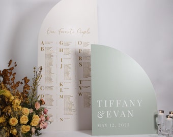 May include: A wedding seating chart with the text "Our favorite people" and a list of names in alphabetical order. A separate sign with the text "Tiffany & Evan" and the date "May 12, 2023" is in front of the seating chart.
