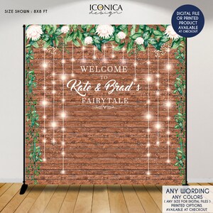 May include: A rustic wooden backdrop with greenery and white flowers. The text "Welcome to Rate & Brad's Fairytale" is written in white script. The backdrop is 8x8 feet.
