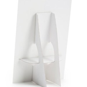 May include: White cardboard display stand with a rectangular base and two vertical supports. The stand is designed to hold a sign or poster.