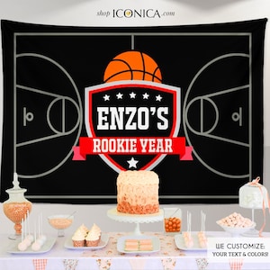 Pu&ograve; includere: Sfondo da basket in bianco e nero con uno scudo rosso e bianco con il testo "ENZO'S ROOKIE YEAR" e una grafica di pallacanestro. Lo sfondo &egrave; esposto su un tavolo con una torta, cupcake e altre decorazioni per feste.
